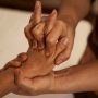 Massotherapist stretching patient digits during Thai massage session